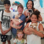Family with children holding young puppies at the island animals rescue, with rescue dogs